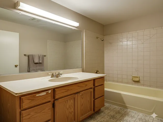 Outdated bathroom with worn vanity and yellowed tub before remodel